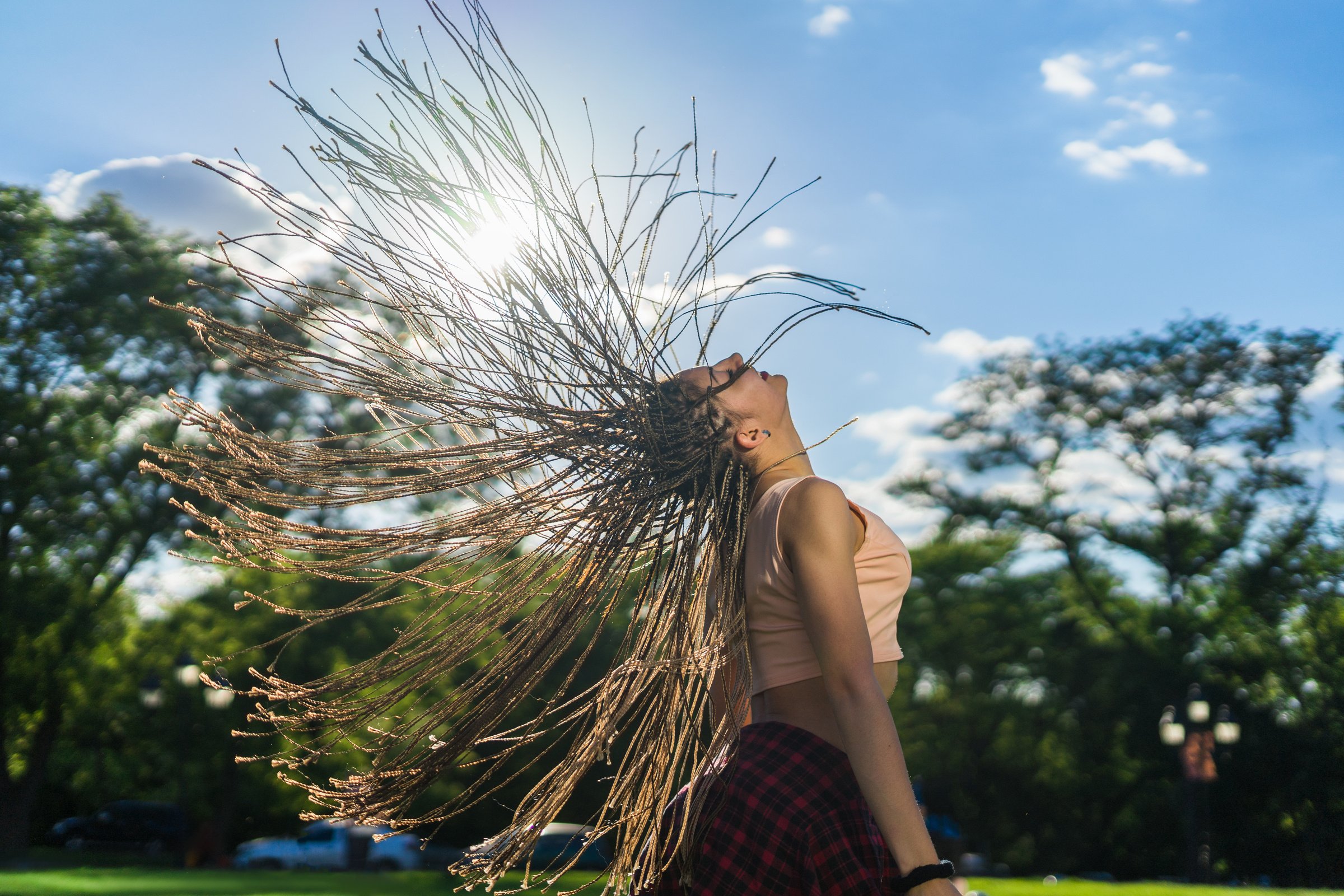 carefree girl with zizi cornrows dreadlocks dancing on green lawn